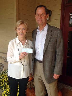 Charlie Caswell delivers check to Sally Hale the Executive Director of Camp Sunshine